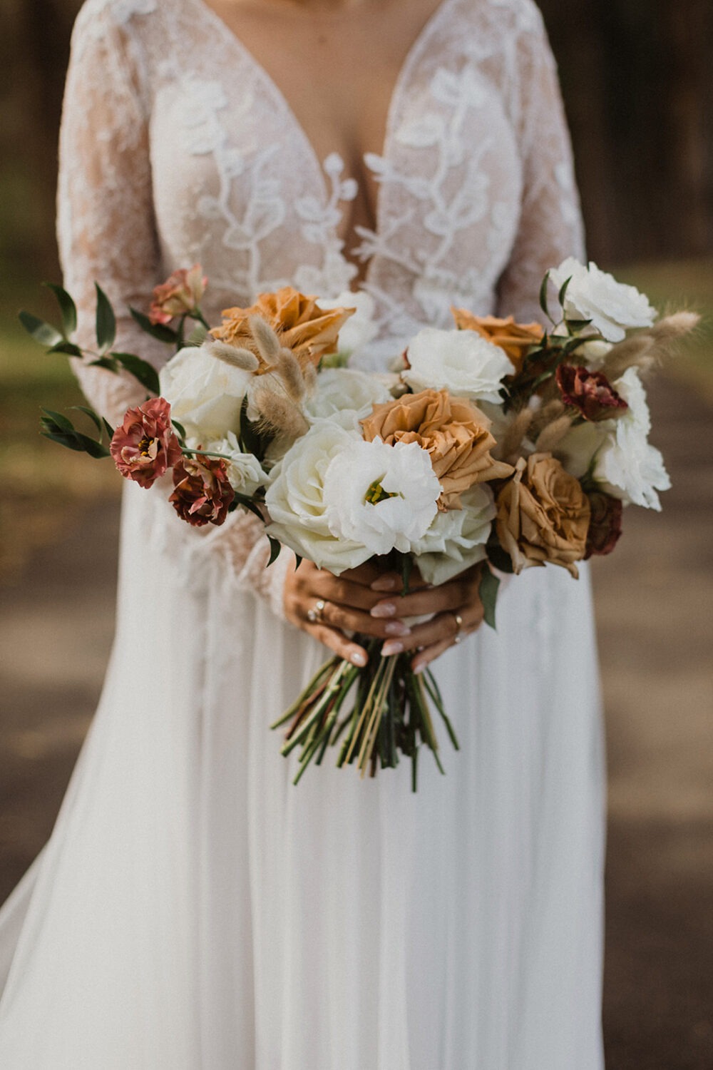 bride holds fall colors wedding bouquet at outdoor wedding 