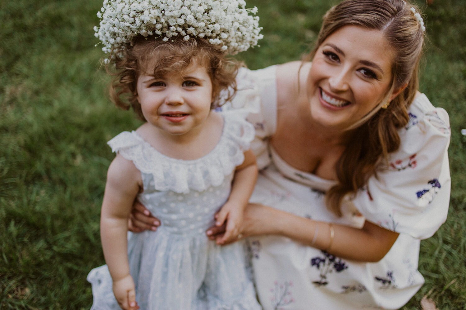 bride holds flower girl wearing flower crown