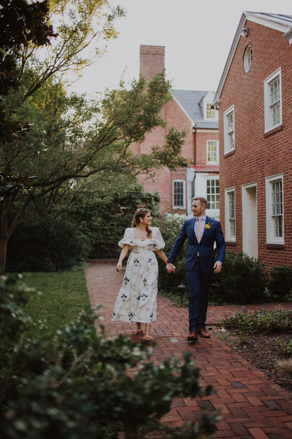 couple walks through brick walkway at backyard garden