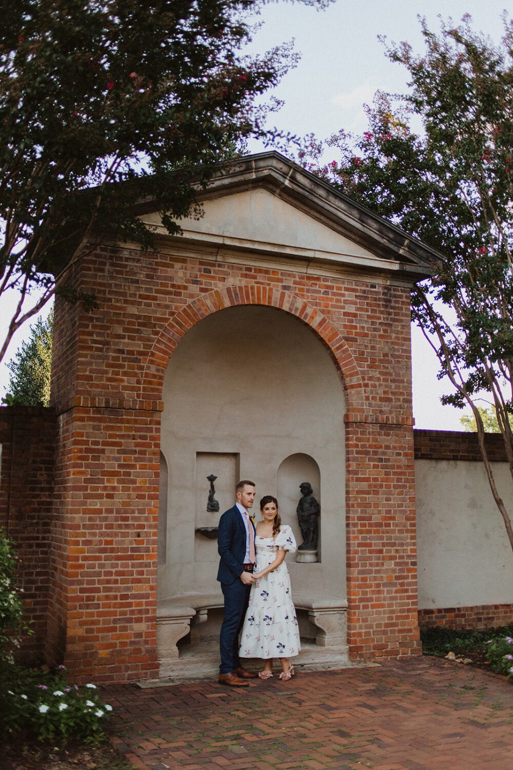 couple poses under brick arch at Dumbarton House garden wedding