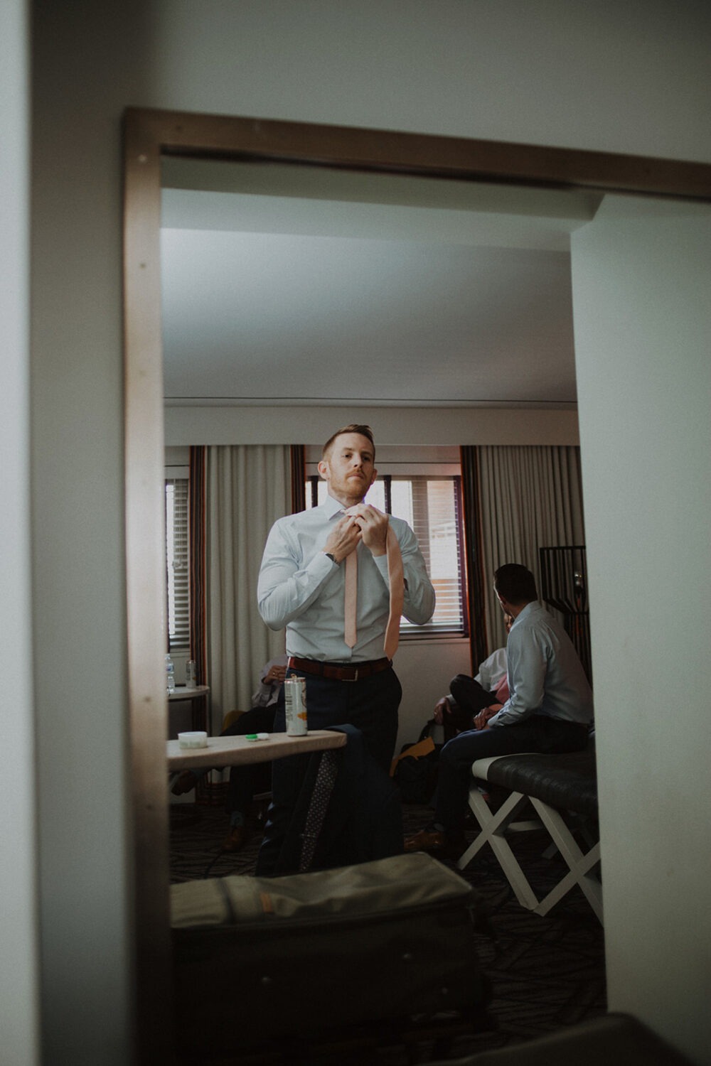 groom ties tie while getting ready for wedding 