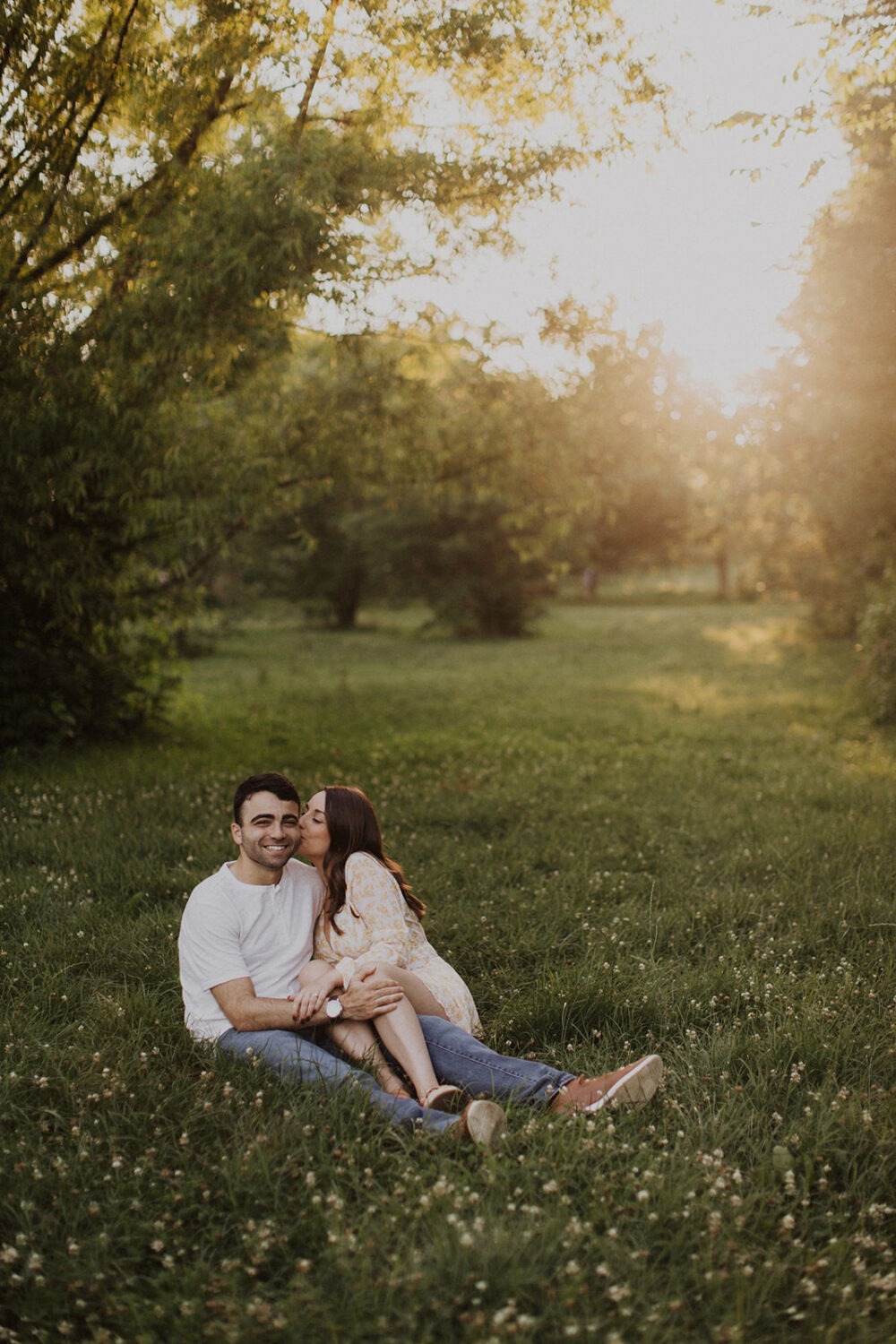 couple kisses sitting in grassy field