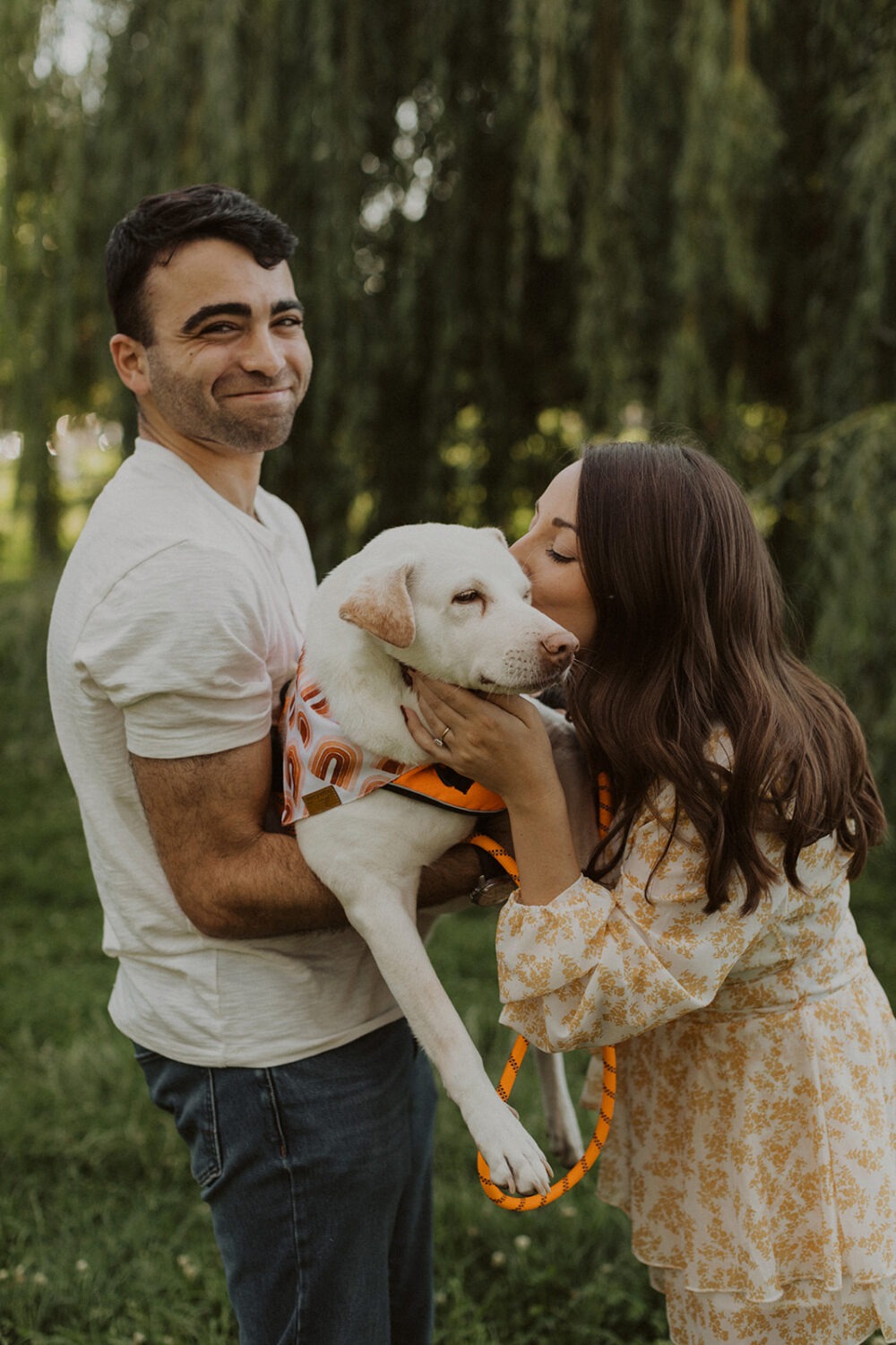 couple kisses dog at outdoor engagement session