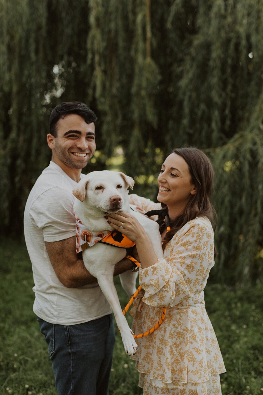 couple holds dog at outdoor engagement session