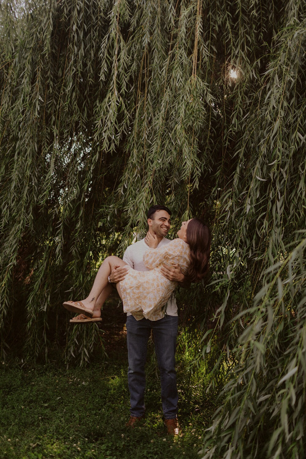 couple embraces under trees during summer engagement photos