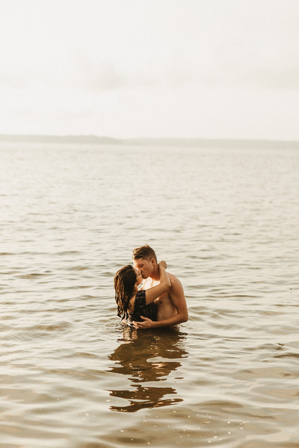 couple kisses standing in lake at engagement session