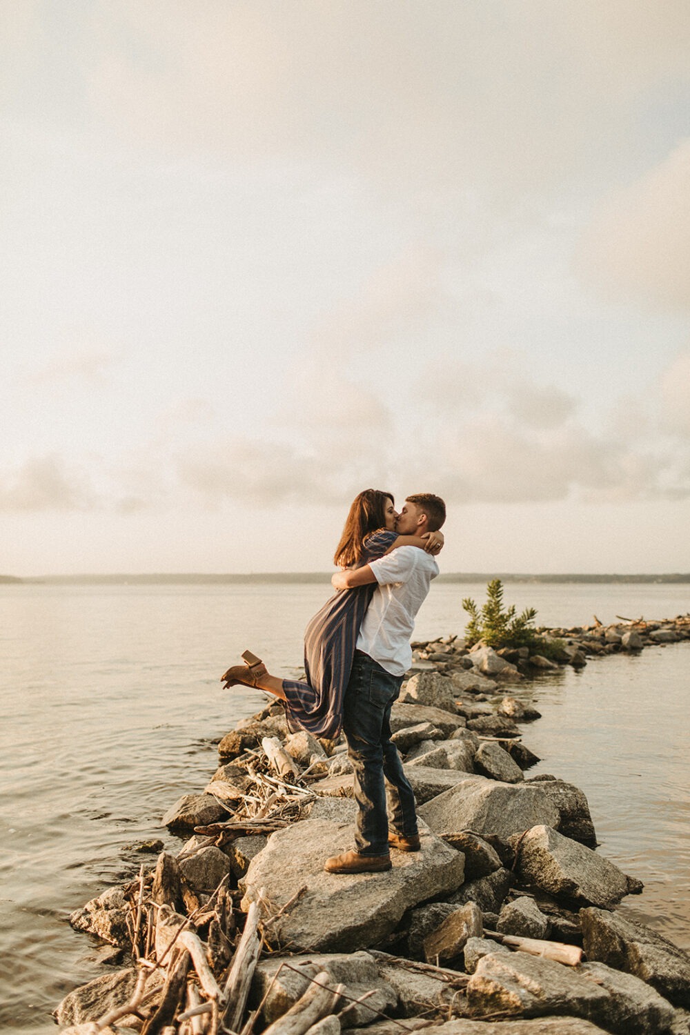 couple kisses at sunrise waterfront engagement session