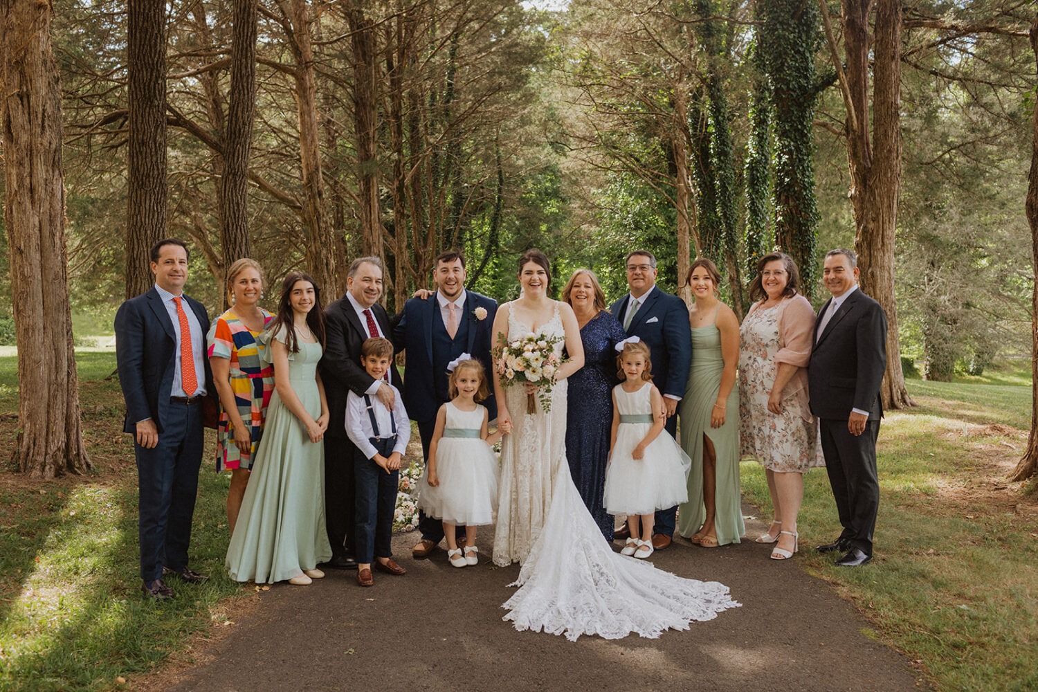 couple poses with family during forest wedding 