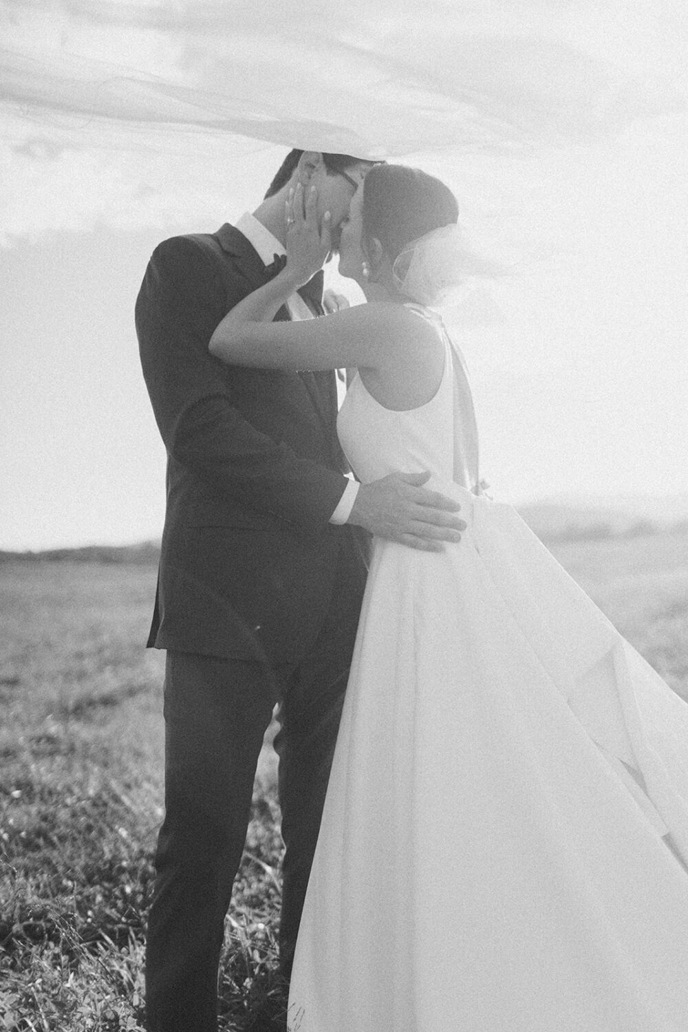 couple kisses under veil trying wedding photo poses