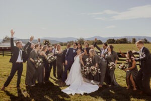 couple poses with wedding party laughing at outdoor wedding