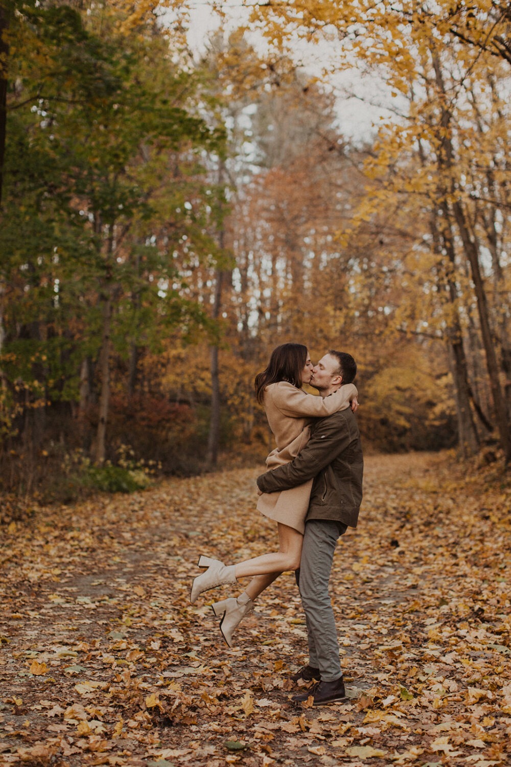 couple kisses wearing fall engagement shoot outfits 