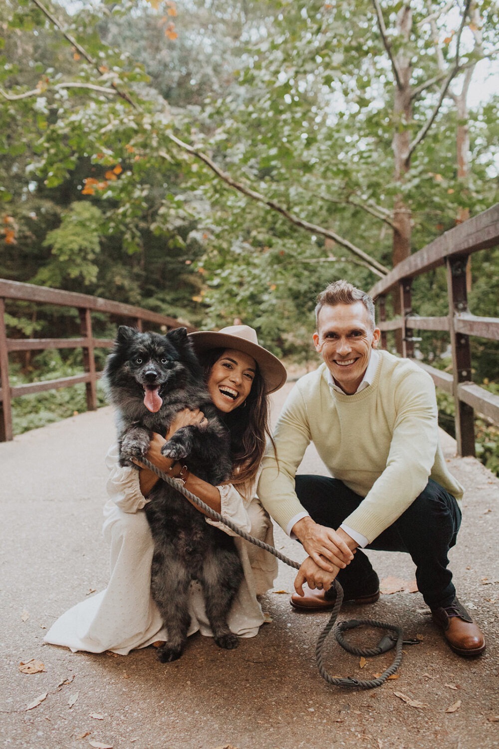 couple poses with dog at white engagement shoot outfit