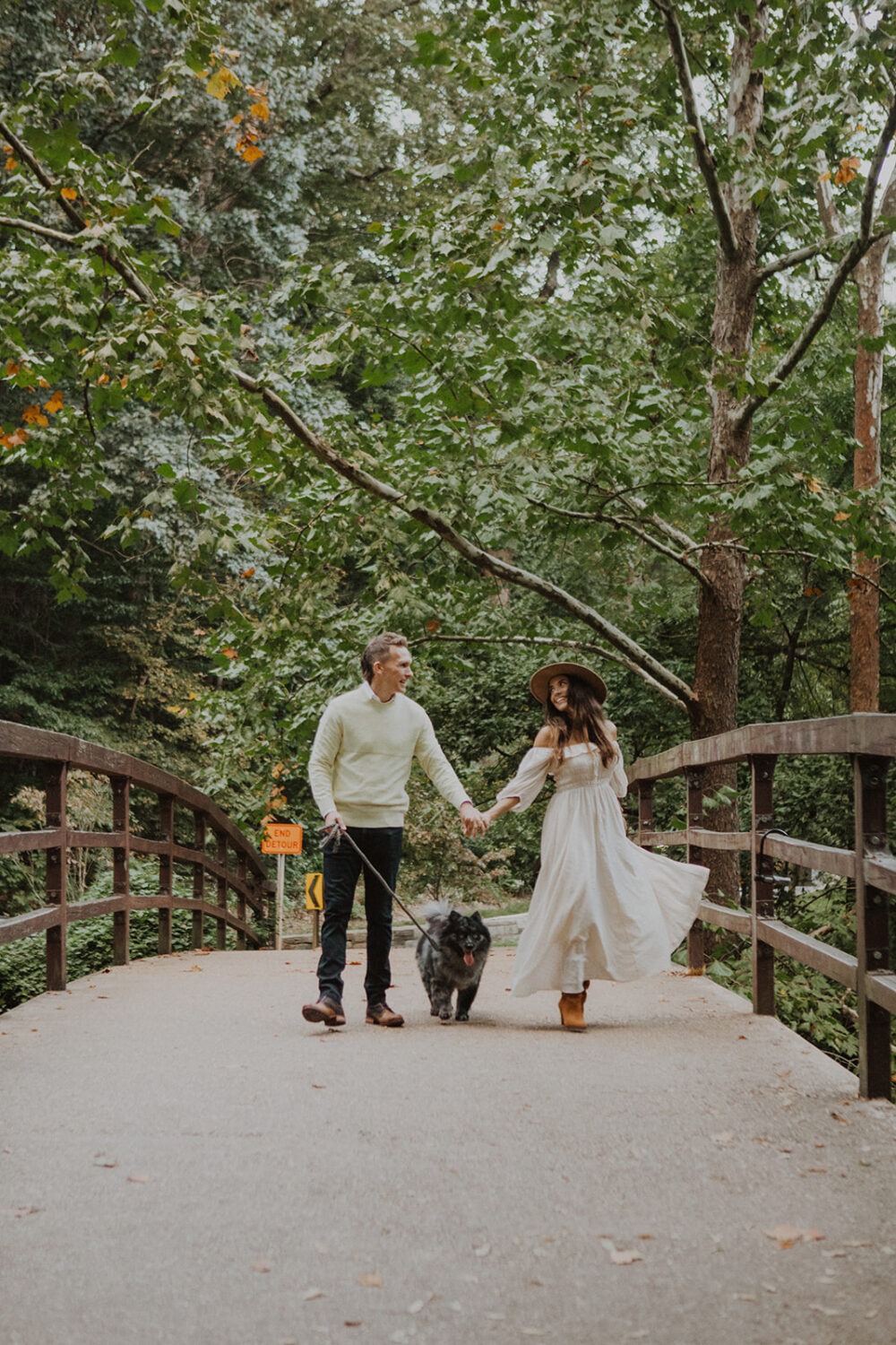 couple twirls in white dress with dog wearing engagement shoot outfit