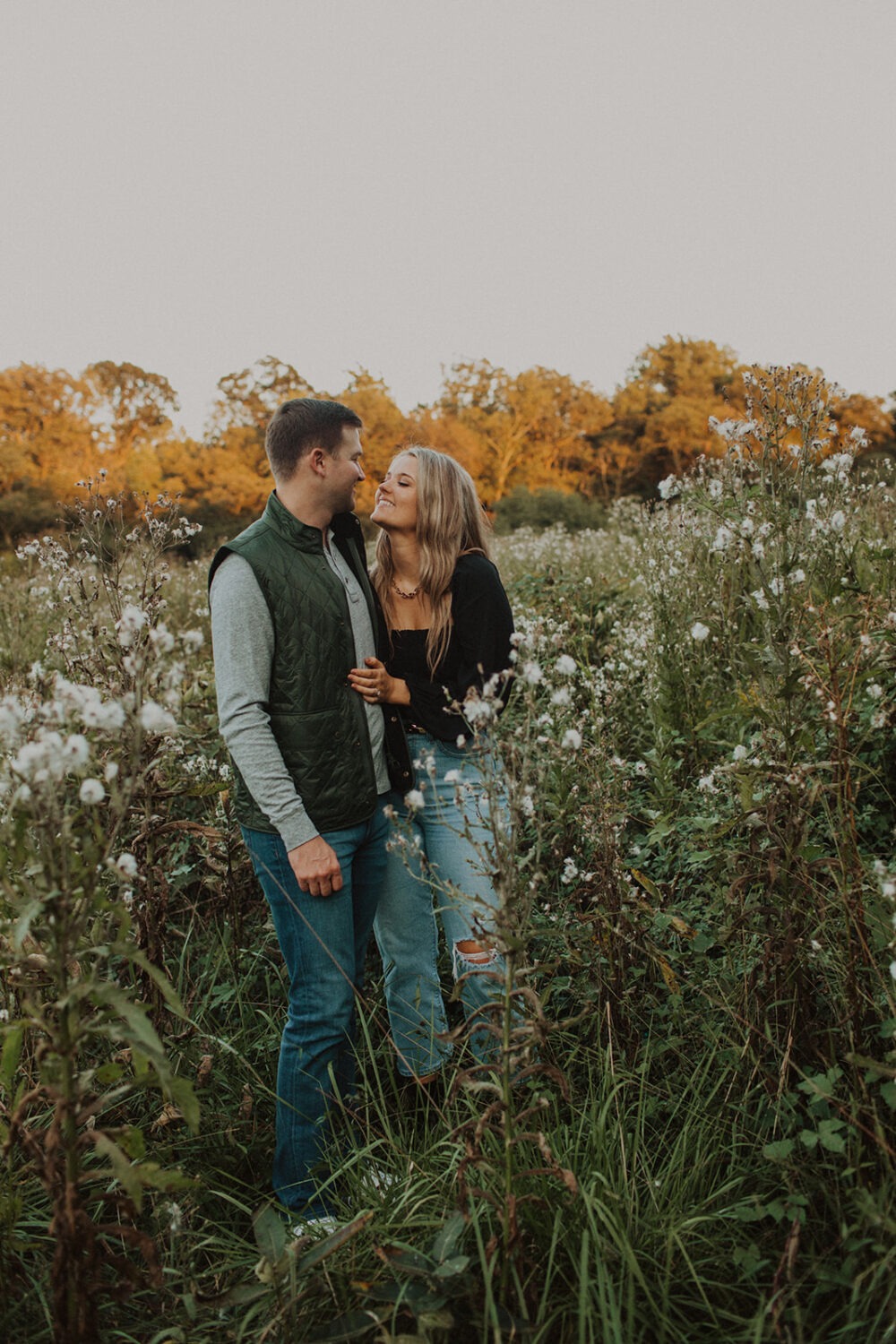 couple embraces in field at sunset engagement session