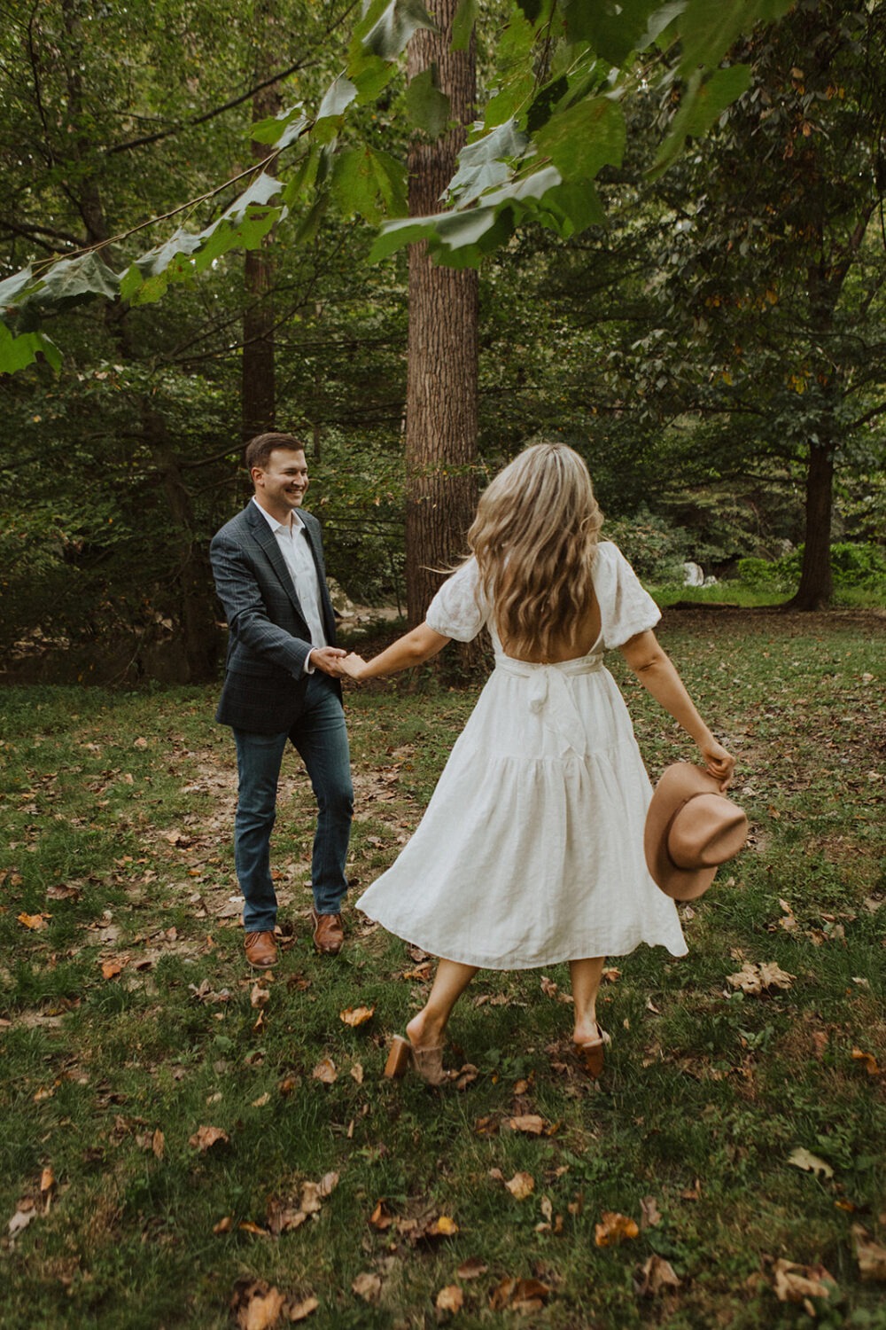 couple runs through forest at fall engagement session