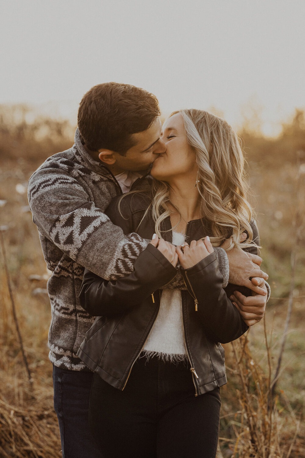 couple kisses wearing engagement shoot outfit 