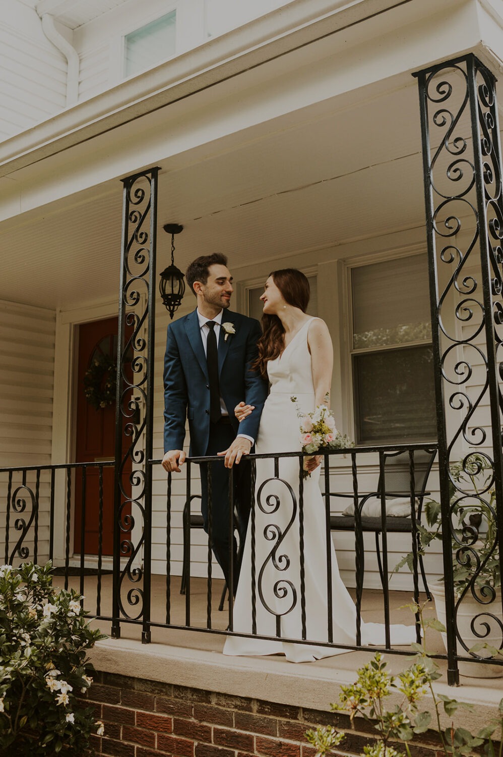 couple stands together on front porch at backyard wedding