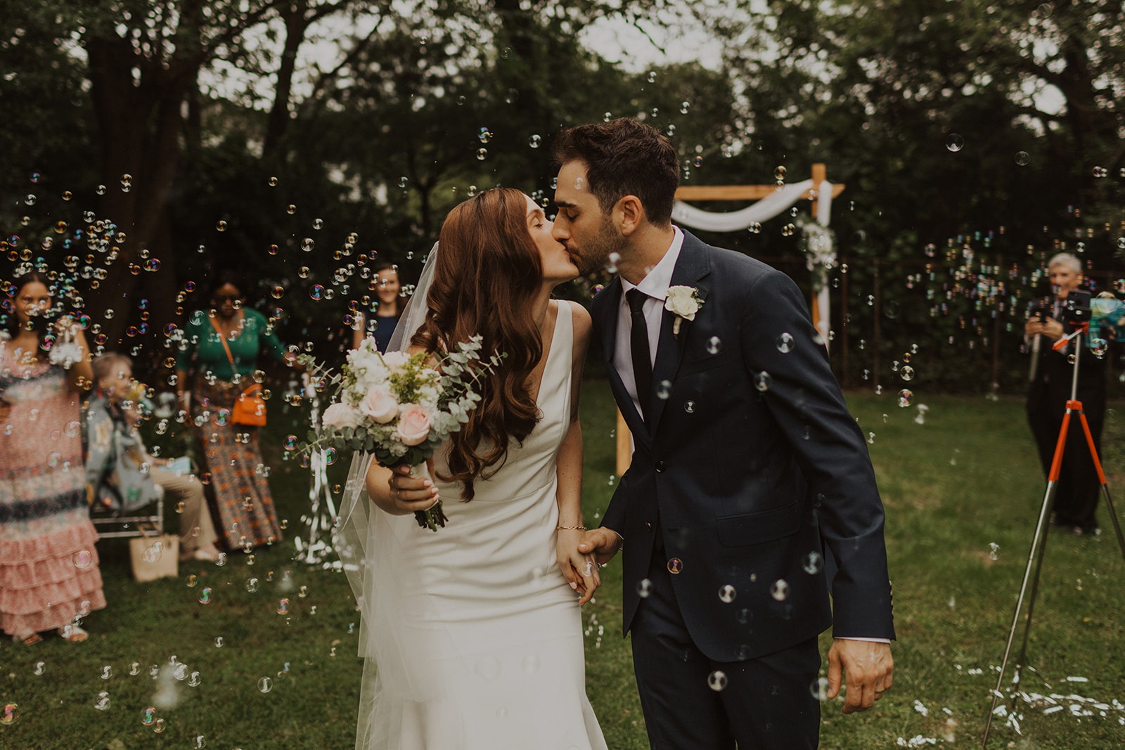 couple kisses during wedding exit with bubbles