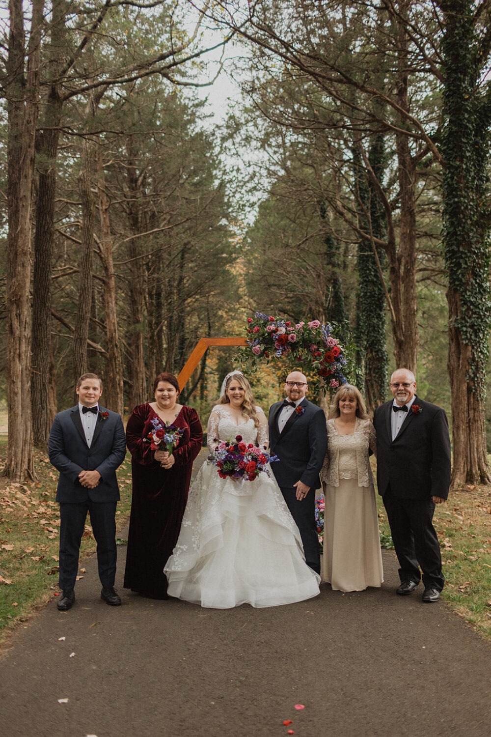 couple poses with family at outdoor fall Poplar Springs wedding