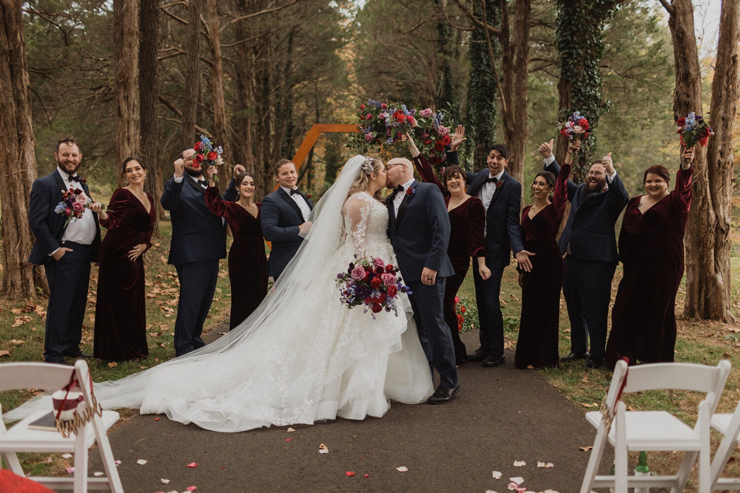 couple kisses with wedding party cheering at outdoor fall Poplar Springs wedding