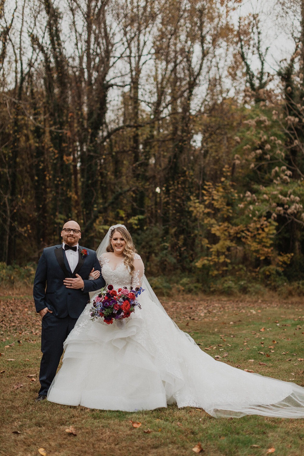 couple stands on fallen leaves at outdoor fall Poplar Springs wedding