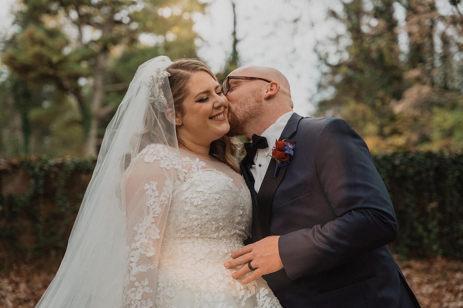 couple kisses at fall forest wedding venue
