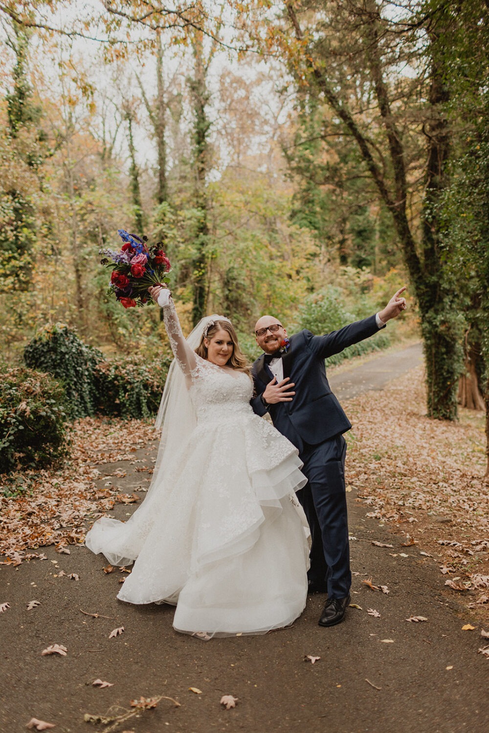 couple cheers together at outdoor fall forest wedding venue