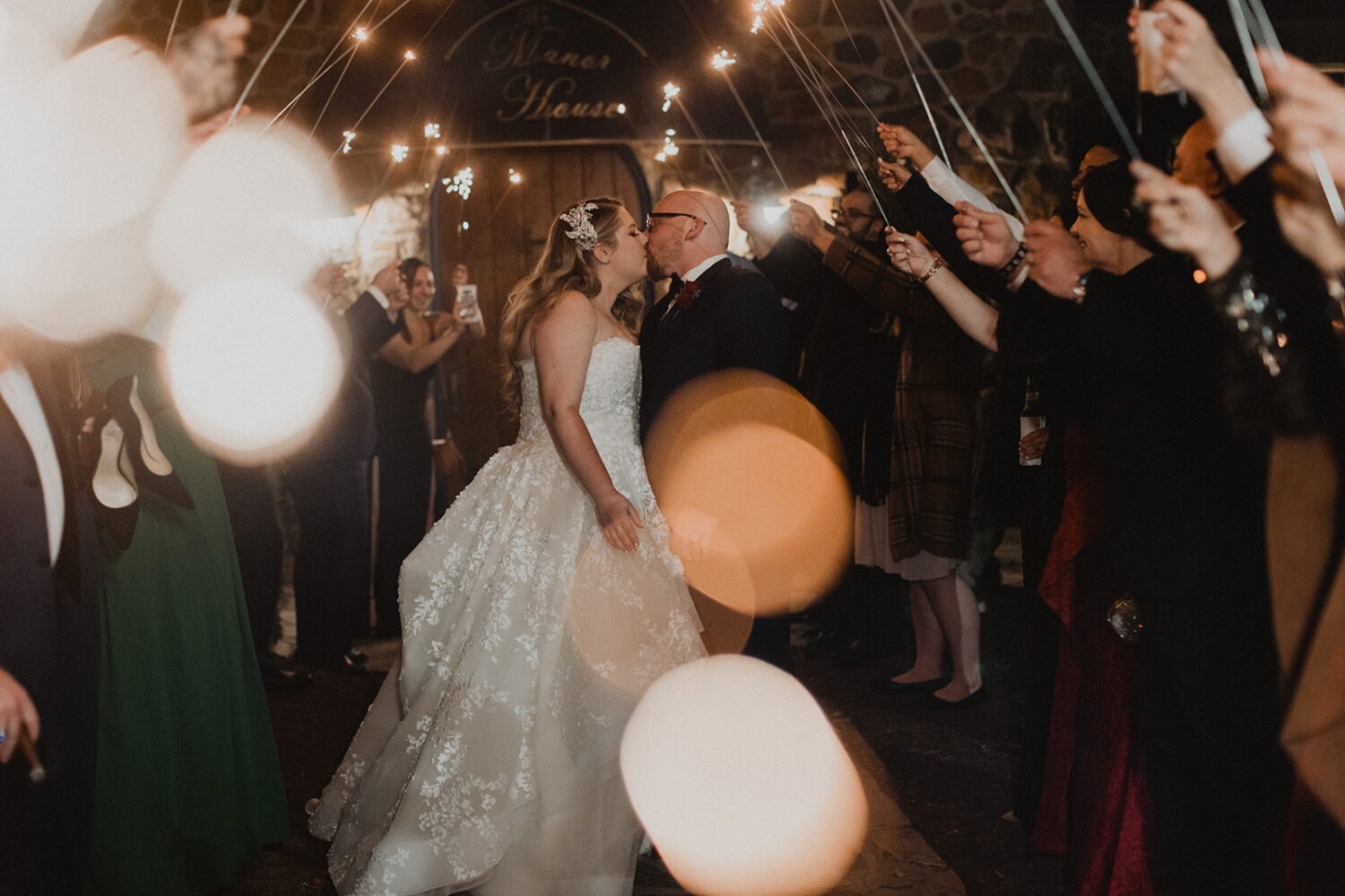 couple kisses during sparkler wedding exit at fall wedding