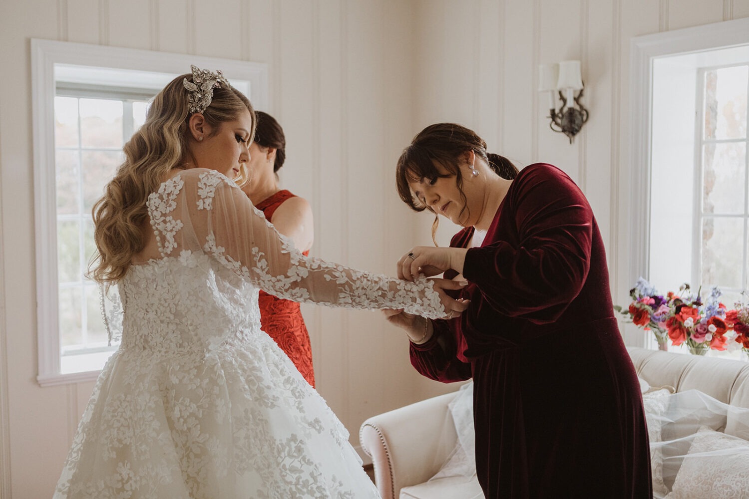 bride has help getting into wedding dress