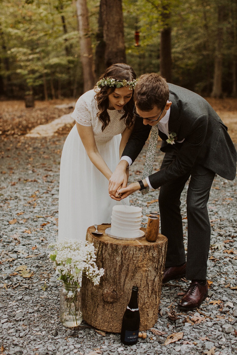 couple cuts cake at woods sunset elopement