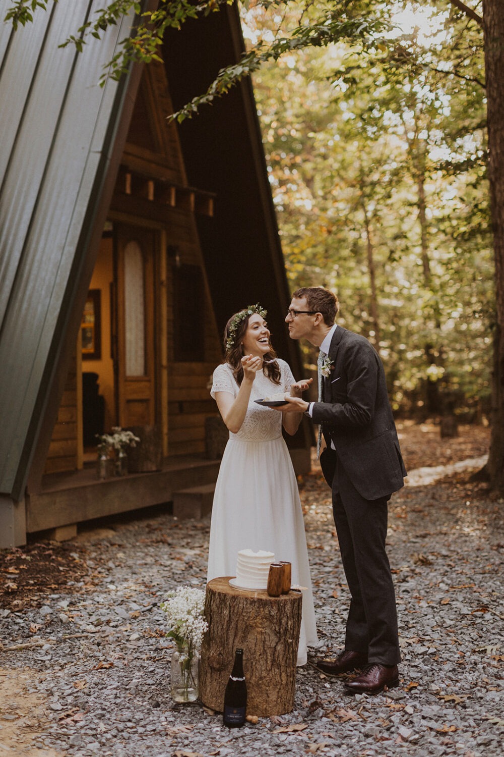couple cuts cake in front of a-frame cabin wedding venue