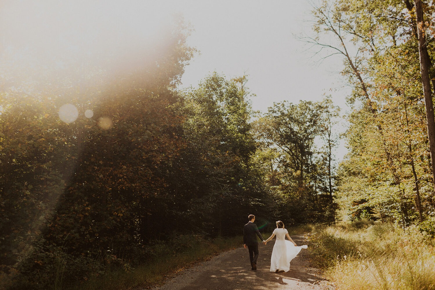 couple walks through woods at Virginia sunset elopement