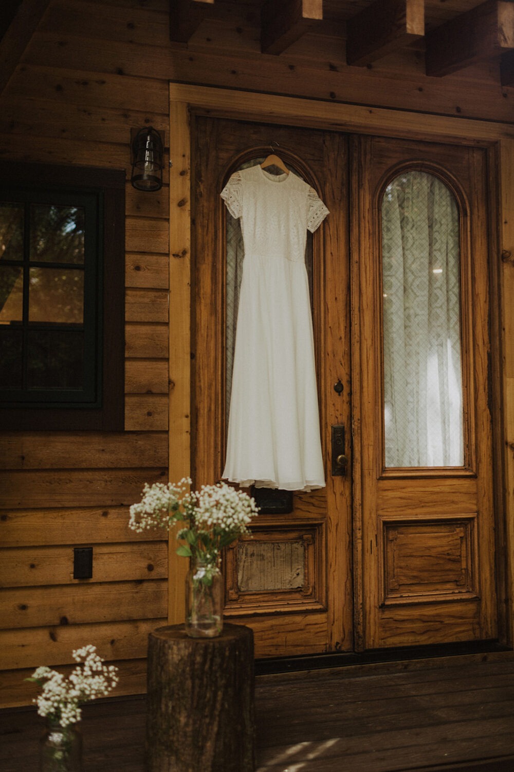 wedding dress hangs over front door of a-frame cabin wedding venue