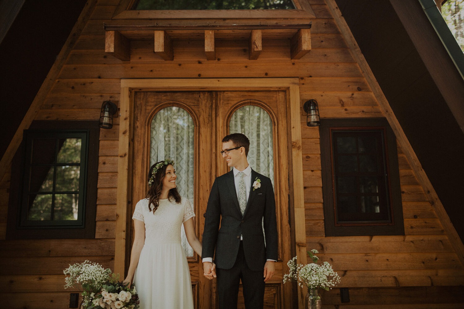 couple holds hands in front of a-frame cabin wedding venue