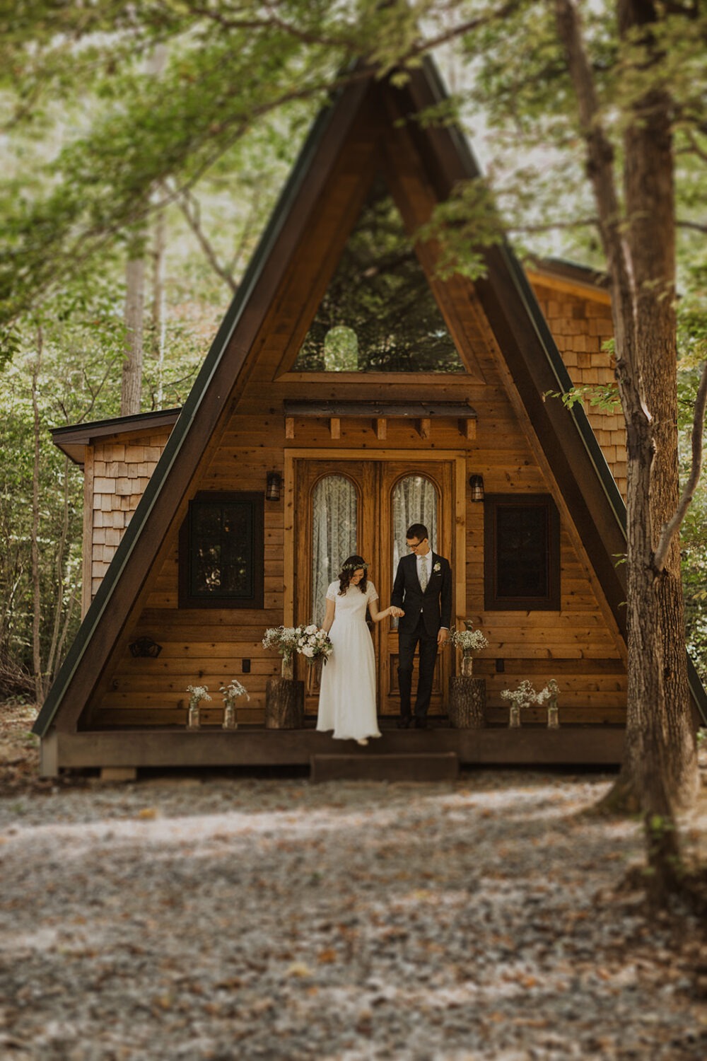couple walks in front of a-frame cabin wedding venue