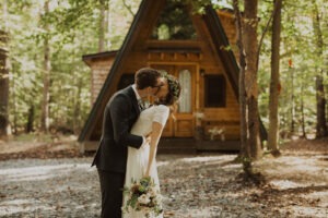 couple kisses at cabin wedding venue