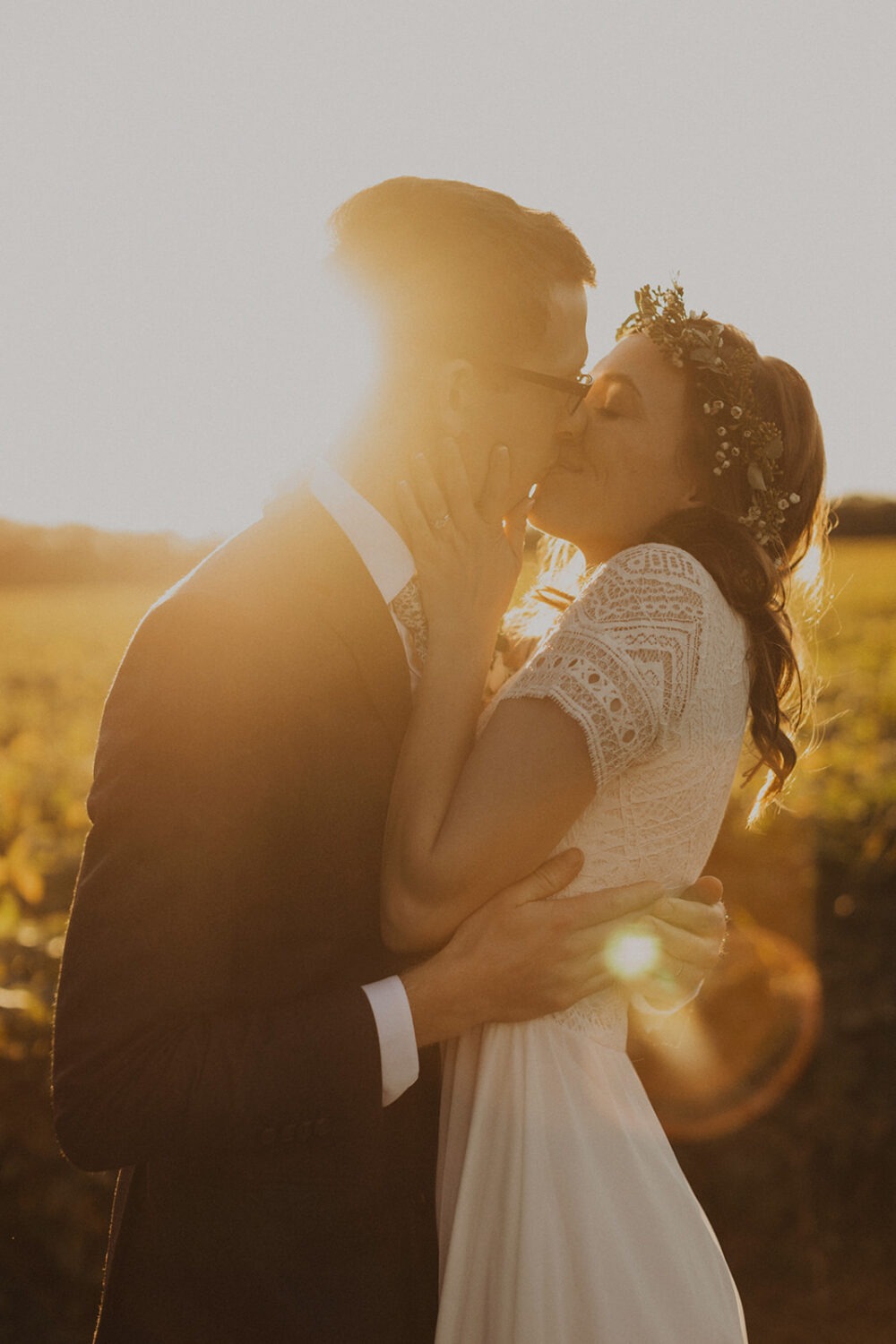 couple kisses in field at sunset elopement