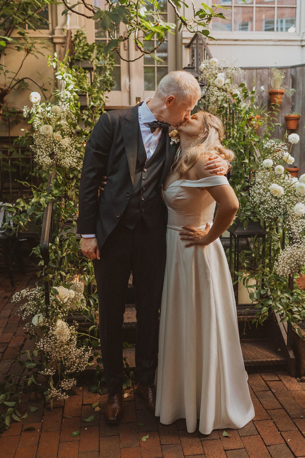 couple kisses in front of white floral wedding decorations at Iron Gate Restaurant DC