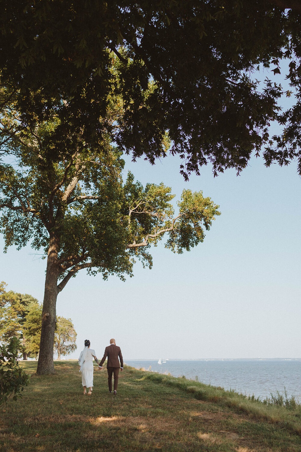 couple walks holding hands along waterfront wedding venue