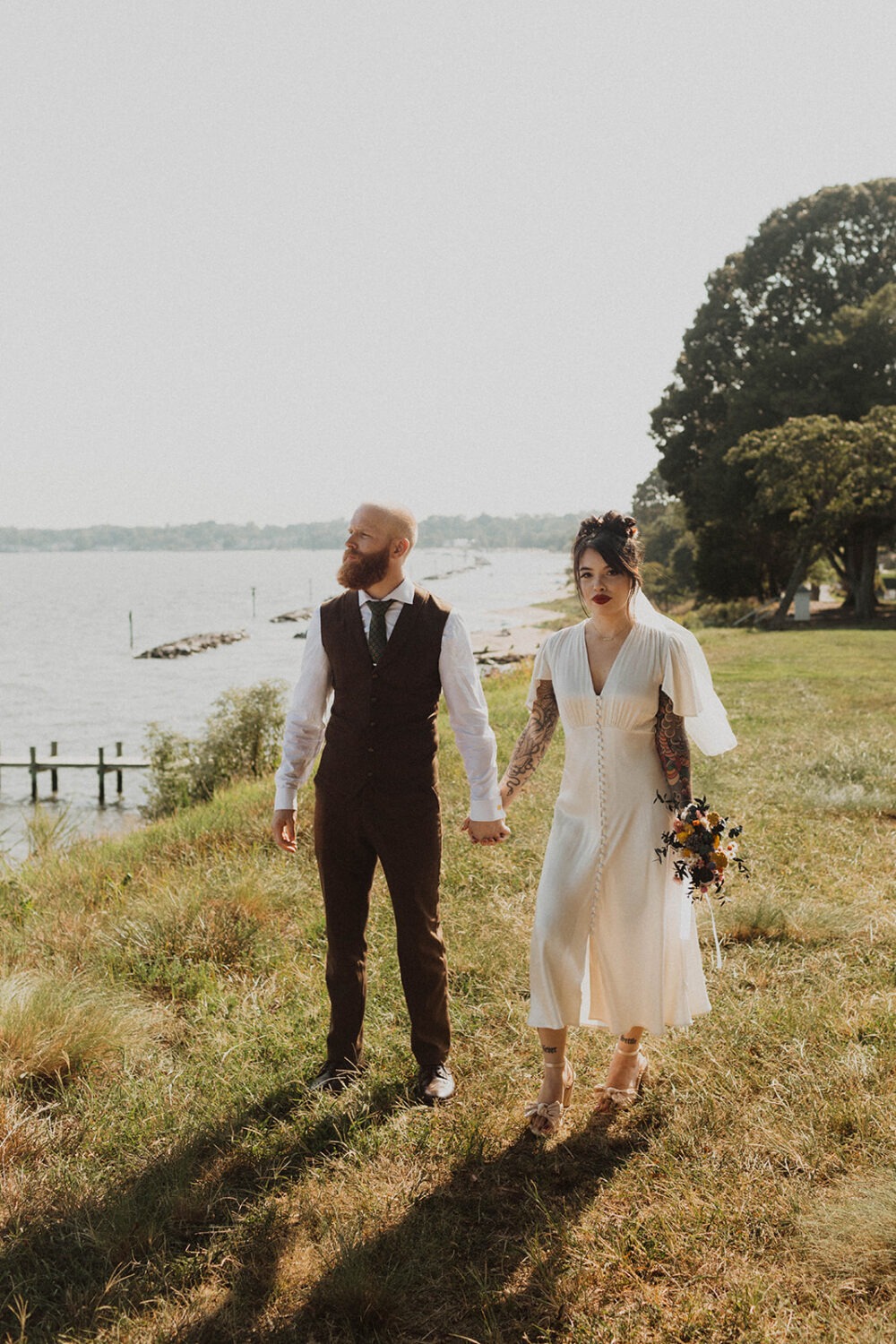 couple walks holding hands along waterfront wedding venue