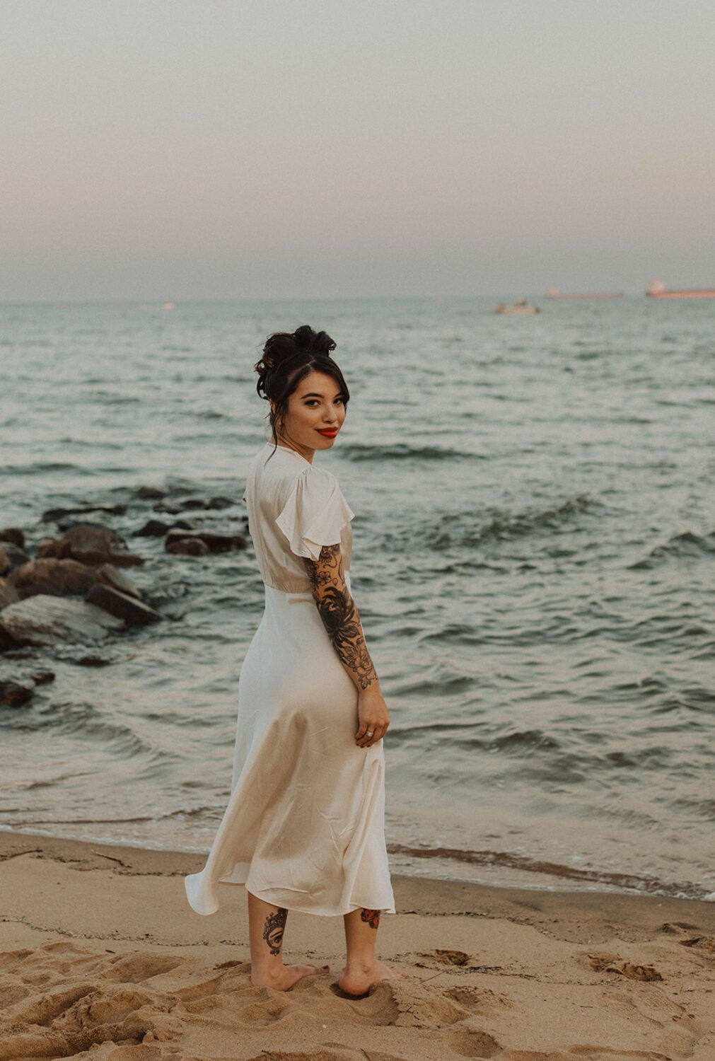 bride stands barefoot along beach