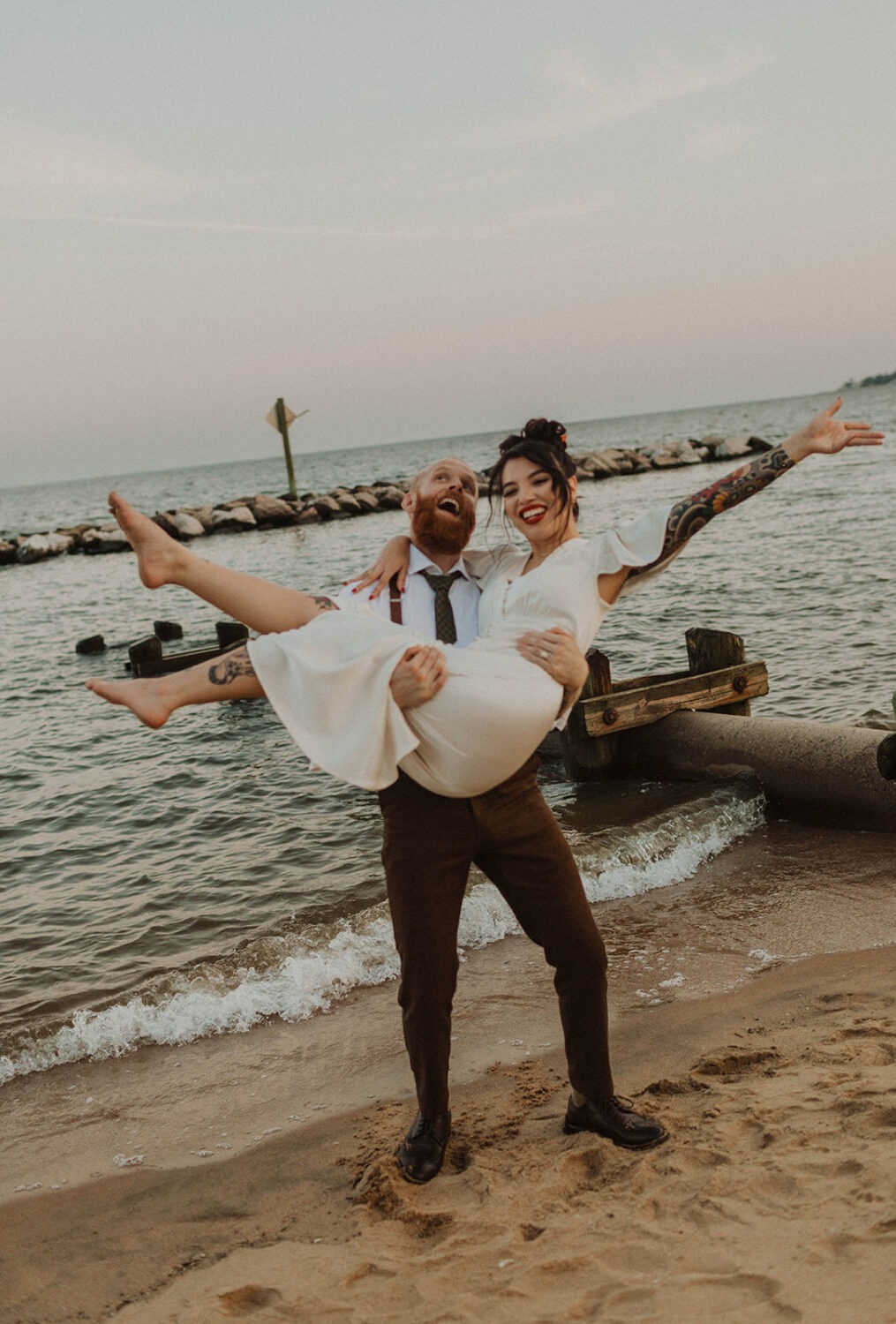 couple embraces along waterfront at beach wedding