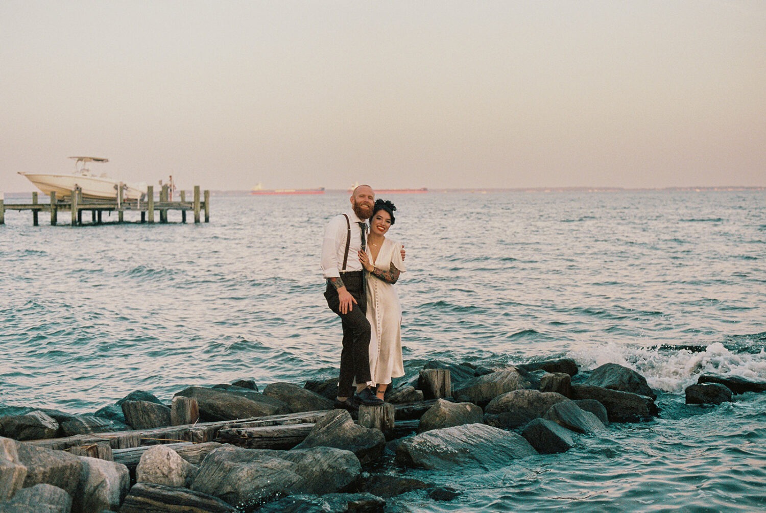 couple stands along waterfront at beach with film wedding photography