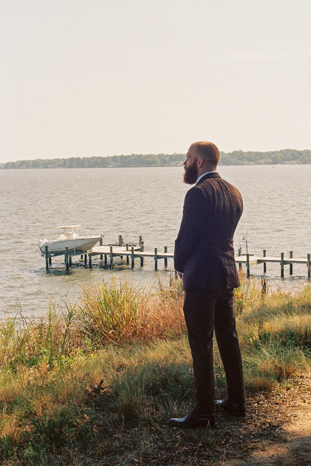 groom stands at waterfront waiting for bride captured by film wedding photography