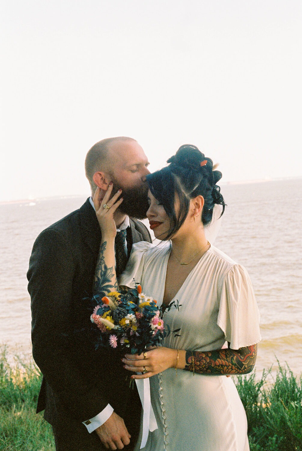 couple kisses at waterfront elopement captured by film wedding photography