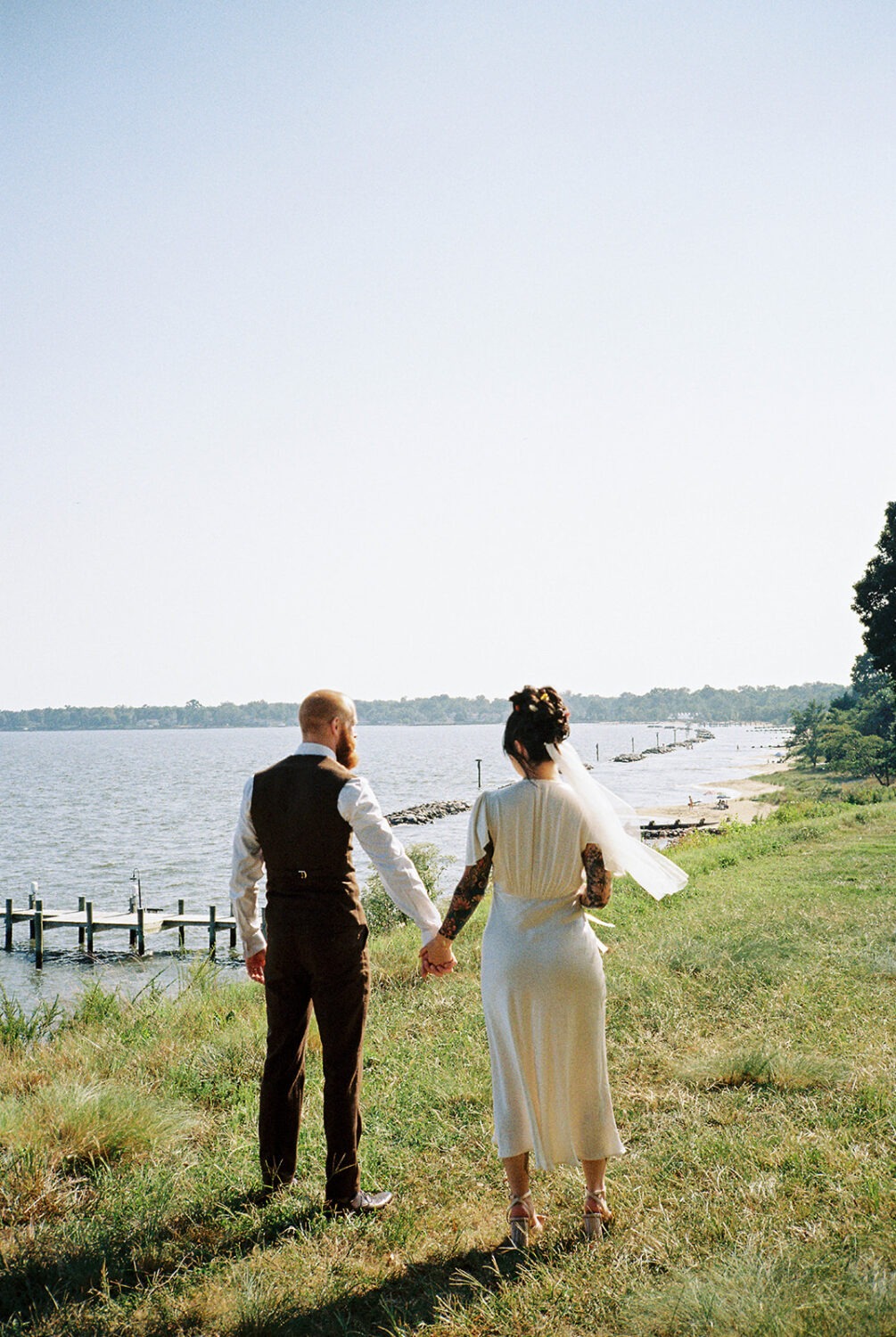 couple walks holding hands captured by film wedding photography