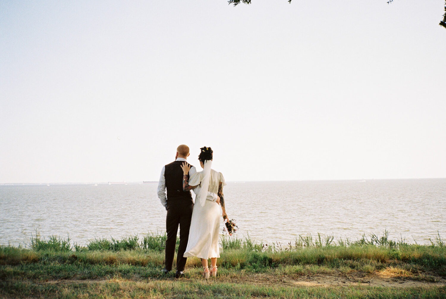 couple embraces by waterfront captured by film wedding photography
