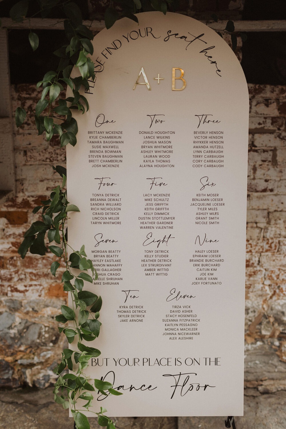 gold and black lettering with greenery on wedding seating chart 