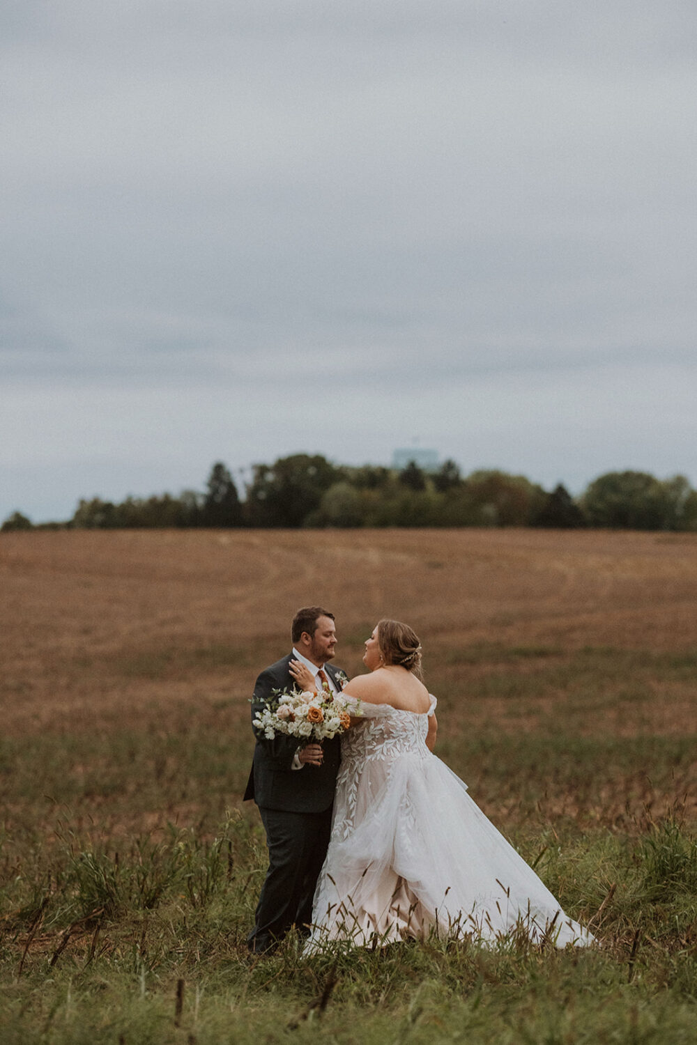 couple embraces at field in Maryland farm wedding venue