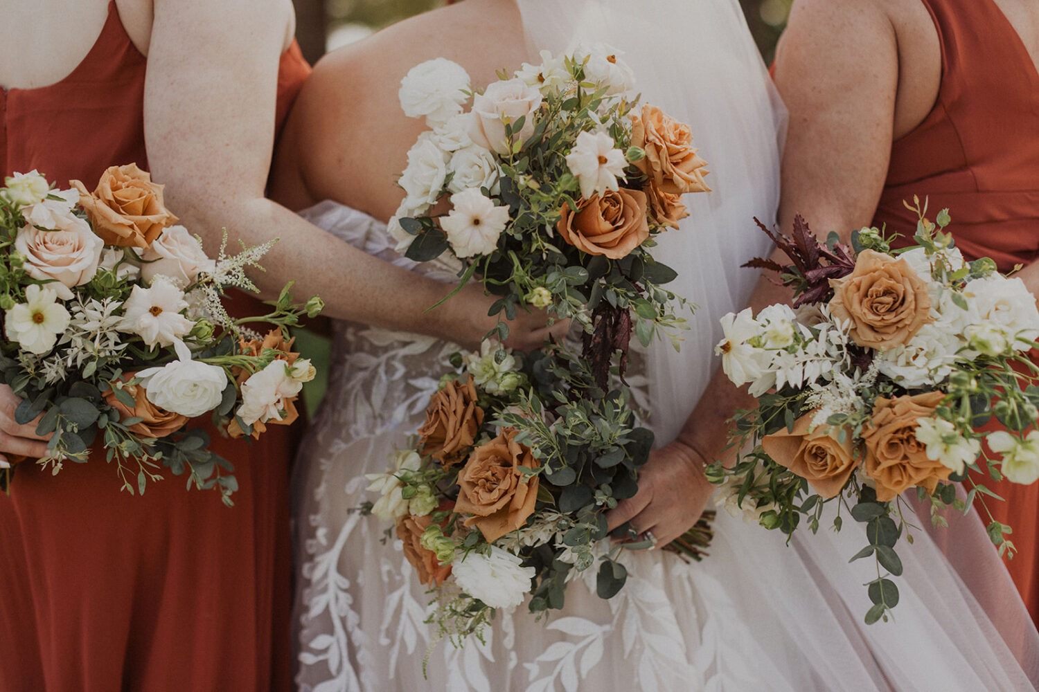 white and orange florals held by bridesmaids and bride